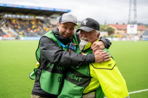 Stian fra Glimtvis og Thor Lihall under kampen mot Linfield på Aspmyra 2022. I grønne vester med akkreditering.