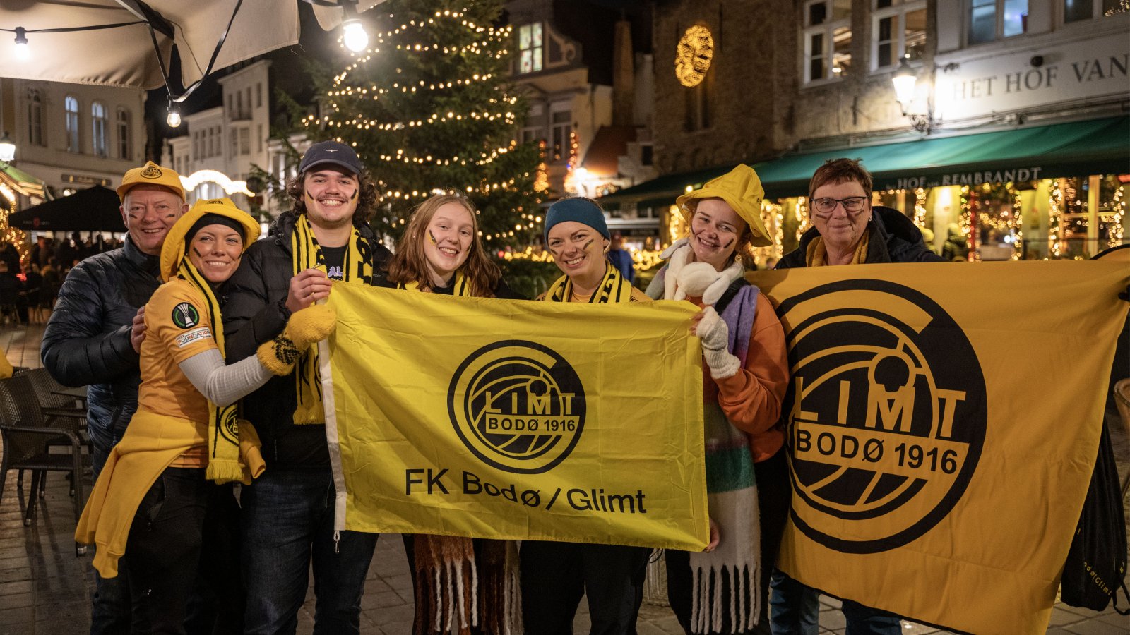 Glimt-supportere poserer med Glimt-flagg på torget i Brugge foran kampen mot Club Brugge i desember 2023