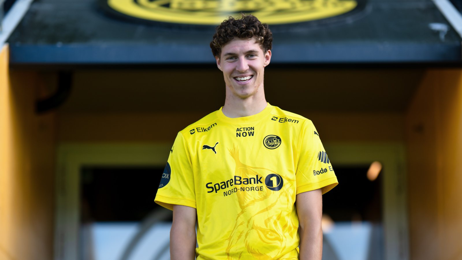 Her står Samuel Burakovsky i gul drakt foran spillerinngangen til Bodø/Glimt