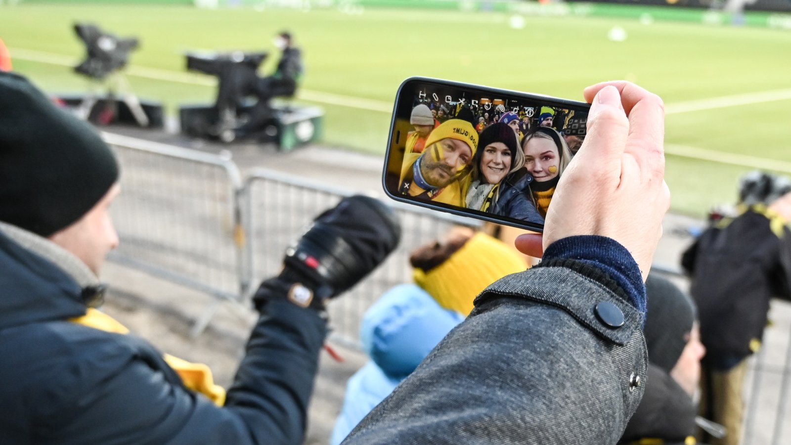 Bilder viser en mobiltelefon som har frontkamera åpent og du ser tydelig tre supportere som tar selfie på Aspmyra før kampen mot Roma i april 2022